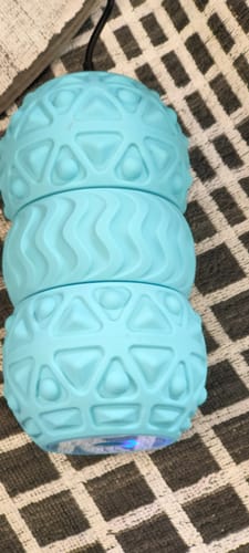 A close-up of the reviewer's light blue Vibit ROLL massage roller, showing its different textured surfaces.