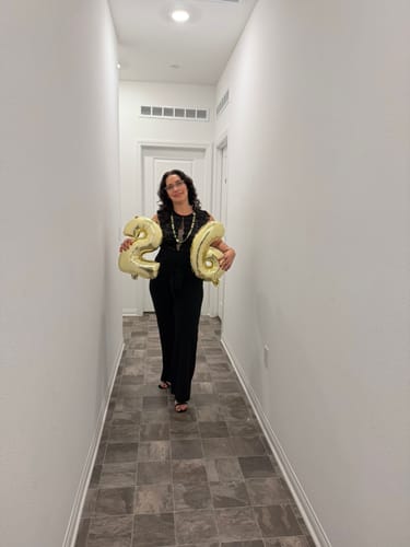 Customer wearing the black Amiliana Lace Top Jumpsuit with wide legs in a hallway.