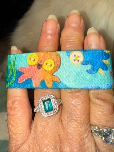 Reviewer holding a colorful wristband from the pack, showing a cute octopus with button eyes.