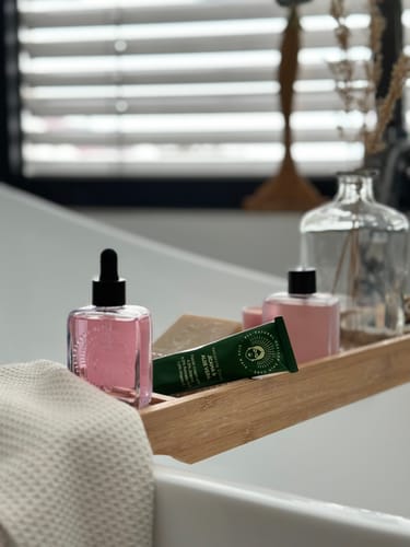 Customer's Barrier Protection Routine with a pink serum and green tube resting on a bath tray.