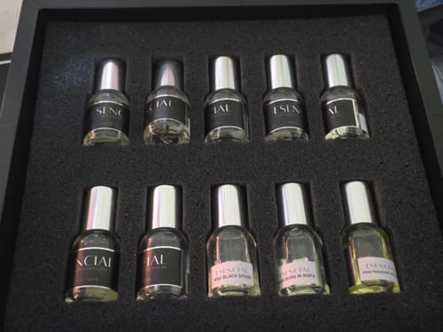 El cliente muestra el set 'Personalizado' de 10 perfumes en su estuche negro.