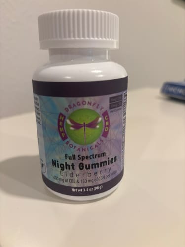 Reviewer's bottle of Dragonfly Botanicals Elderberry CBD Night Gummies sitting on a white surface.