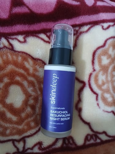 A customer's bottle of Bakuchiol Resurfacing Night Serum resting on a patterned blanket.