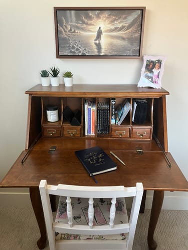 Reviewer's framed painting of Jesus walking on water hanging on a wall above a wooden desk.