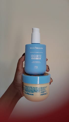 Cliente segurando o Iogurte Hidratante Corporal em frasco azul sobre o pote da Manteiga Hidratante.