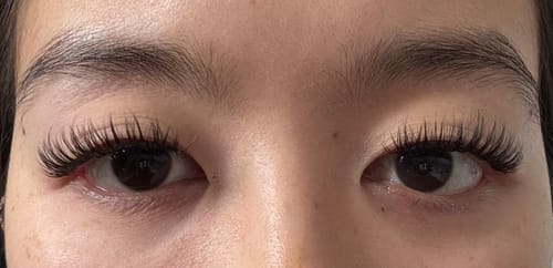 Nahaufnahme der Augen einer Kundin mit angebrachten, voluminösen CAFE GLAM SINGLE Wimpernextensions.