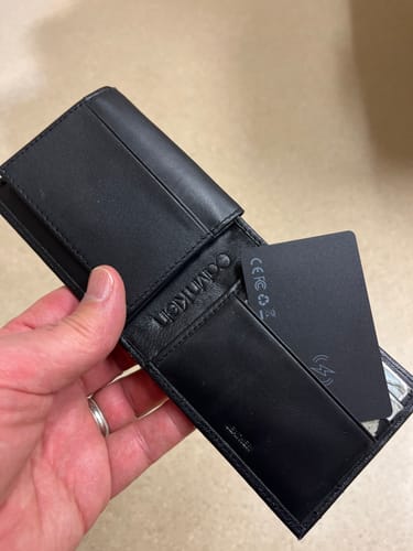Customer holding a black wallet to show the slim SPOTMINDERS Tracking Card fitting into a card slot.