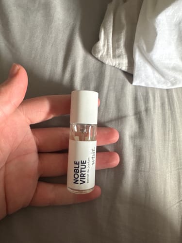 Reviewer holding the Mystery Gift, a small sample bottle of 'Noble Virtue' cologne.