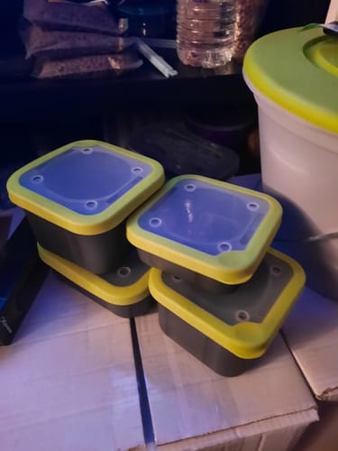 Recensent toont vier grijze BAIT BOXES Solid Top met limoengroene deksels op elkaar gestapeld.