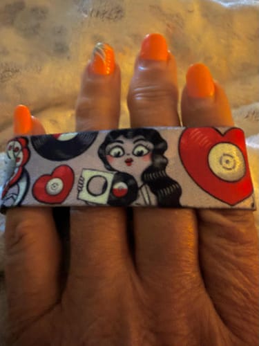 Close-up of a customer's hand showing a wristband from the Pick-A-Door Mystery 3-Pack with a colorful record-themed design.