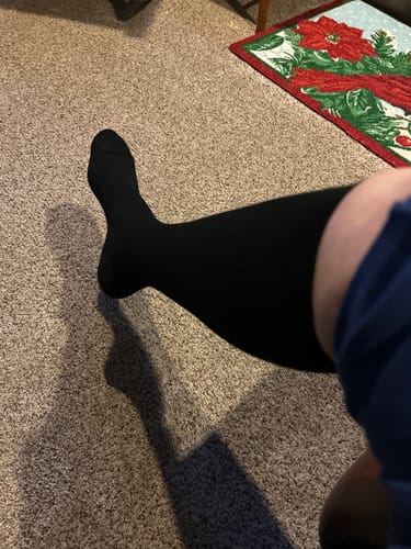 A reviewer's leg wearing the black Eucalyptus Compression Socks while seated indoors.