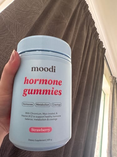 Customer holding a light blue jar of moodi Strawberry Hormone Gummies.