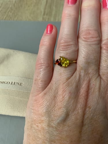 Customer wearing the Leesha Birthstone Ring on their finger, featuring a yellow and a red stone.