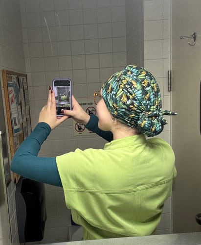 Reviewer's mirror selfie showing the back of their patterned head scrub, tied neatly in a bun.