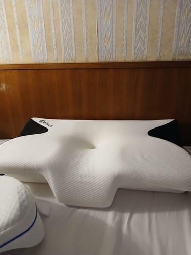 Le coussin d'alignement cervical Cellsius d'un client, blanc et ergonomique, posé sur un lit.