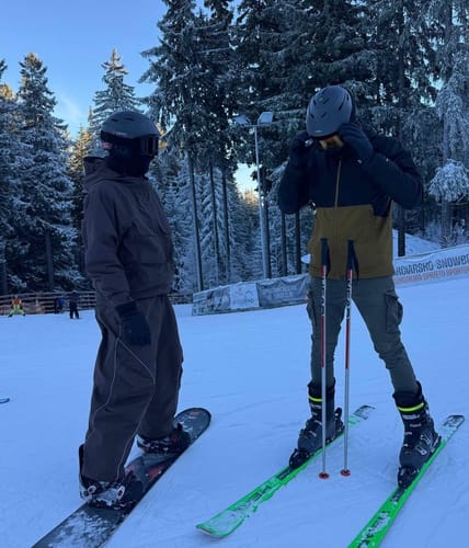Reviewer standing on a snowy slope wearing the coffee and black Half-Zip Insulated Snow Anorak.