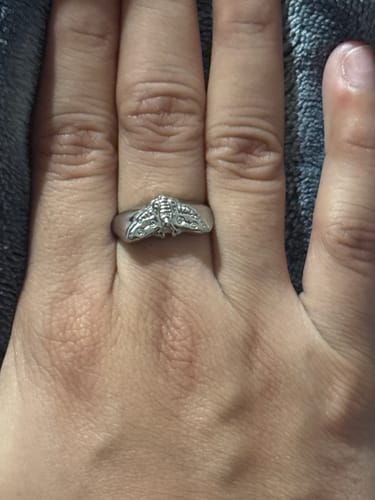 A reviewer's hand wearing the detailed MOTH RING on their middle finger.