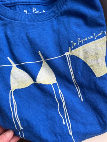 Customer's blue air dry baby tee, showing the full bikini graphic with a faded yellow print.