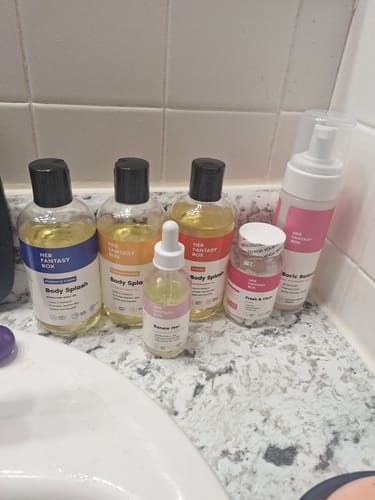 Reviewer's collection of Her Fantasy Starter Kit products arranged on a bathroom counter by the sink.