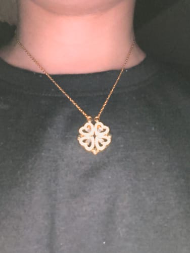 Customer wearing a gold-colored necklace with a decorative four-leaf clover pendant.
