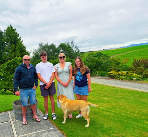 Reviewer's daughter wearing the blue graphic sandy baby tee while posing outdoors with her family.