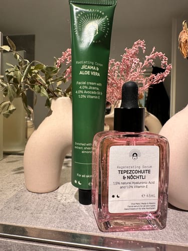 Customer's Glow Infusion Duo, a green cream tube and pink serum bottle, on a bathroom shelf.
