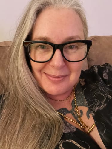 Reviewer smiling in a close-up, wearing the chunky gold XL T-Bar Necklace.