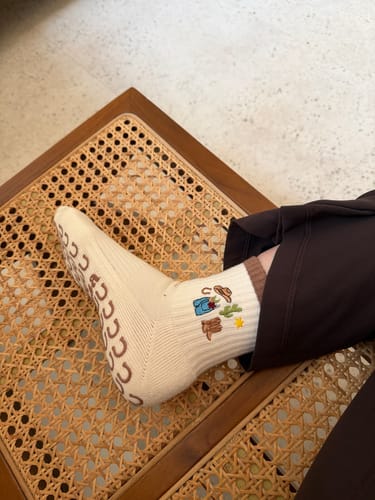 Customer wearing the off-white Cowgirl socks, showing embroidered boot, hat, and star details.
