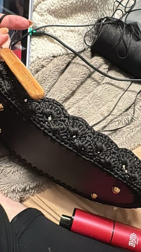 Close-up of a customer crocheting the black Aveline Shoulder Bag from the kit, showing the hook and leather base.