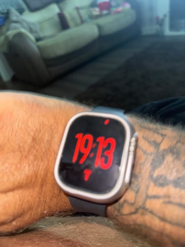 Customer's Apple Watch Ultra on wrist, displaying time in red on the screen.