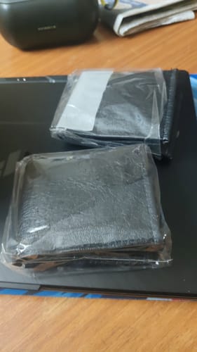 Customer's Spiderman wallet, showing two black wallets in clear plastic packaging on a desk.