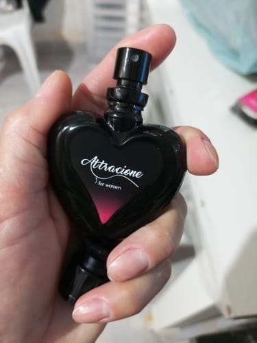 Customer's Attracione Sensual heart-shaped perfume bottle held in hand, featuring a black design with pink accents.