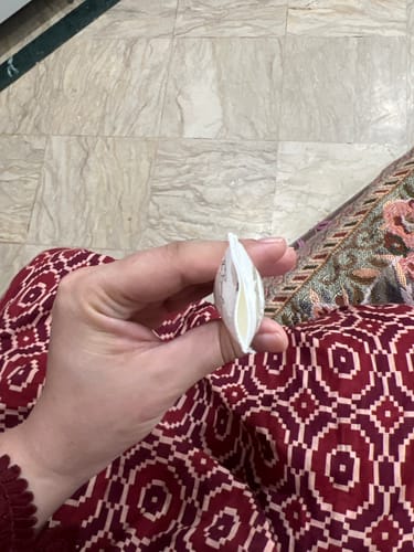 Reviewer's hand holding a damaged and torn Lip Cream tube, showing a split seam at the end