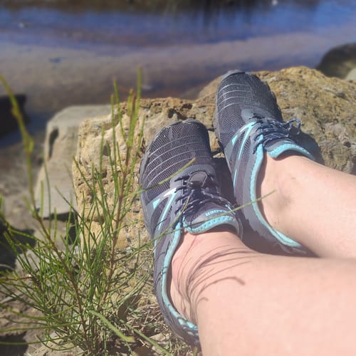 Customer's Women’s Barefoot Minimalist shoes resting on a rock near water.