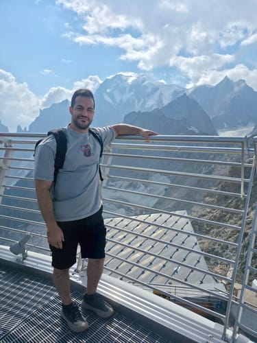 Reviewer wearing the light gray ALCHEMY WASH TEE with a backpack on a mountain overlook.