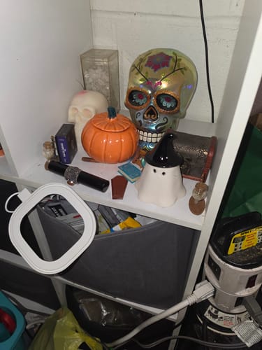 Customer's Halloween Mystery Box items including a ceramic pumpkin jar, ghost incense burner, and skull figurine on shelf.