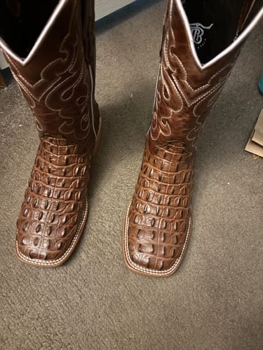 Customer's brown caiman hornback leather boots with square toes standing on carpeted floor.