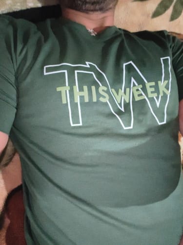 Customer's green Theo short sleeve t-shirt worn by a person, showing the white graphic text design.