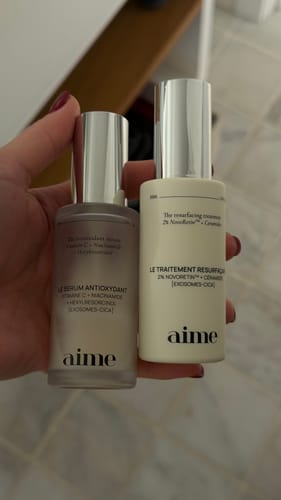 Reviewer's hand holding Le traitement resurfaçant alongside a serum bottle.