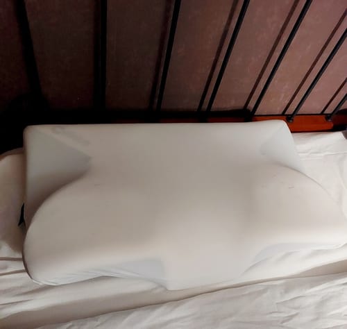 Customer's white Oreiller Papillon Cervical Cellsius pillow resting on a white bed sheet.
