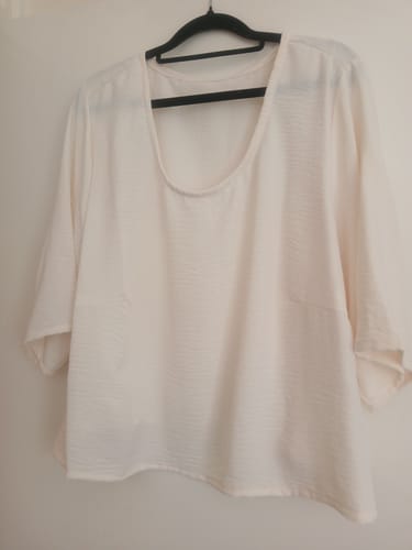 Customer's cream-colored shirt made from Italian stretch crepe fabric, hanging on a black hanger.