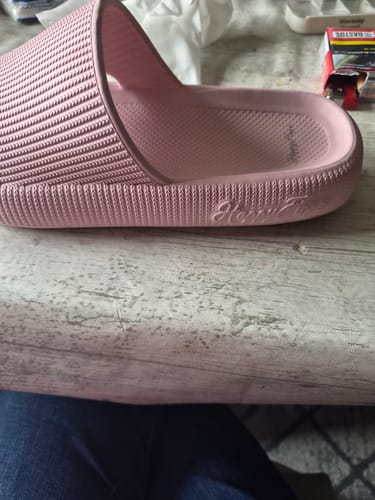 Customer's roze slipper met gestructureerde band en zachte zool, van dichtbij gefotografeerd.