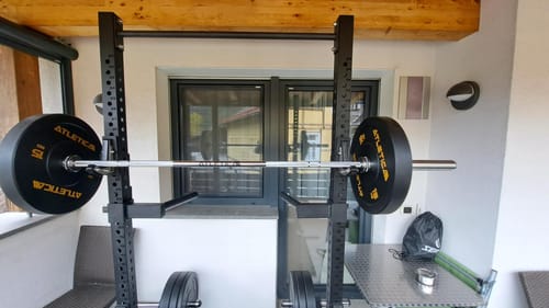 Customer's R7 Outdoor Squat Rack with loaded barbell and weight plates, set up on a covered balcony.
