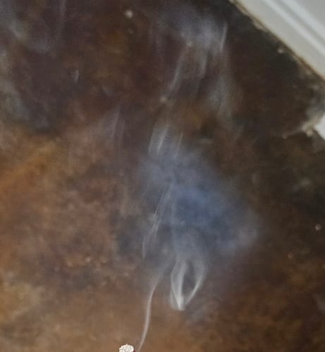 Customer's Acapulco Gold Hash Hole pre-roll burning, producing wispy smoke against a dark, textured background.