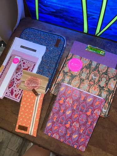 Customer's Planner Folio and patterned notebooks spread out on a wooden table.