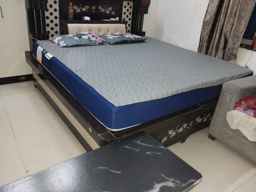 Customer's Flo Mattress Ergo placed on a dark wooden bed frame with a gray patterned mattress surface.