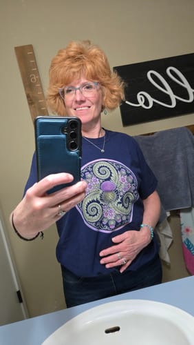 Customer's navy Thistle Triskele Fern T-Shirt showing the botanical design while taking a mirror selfie.