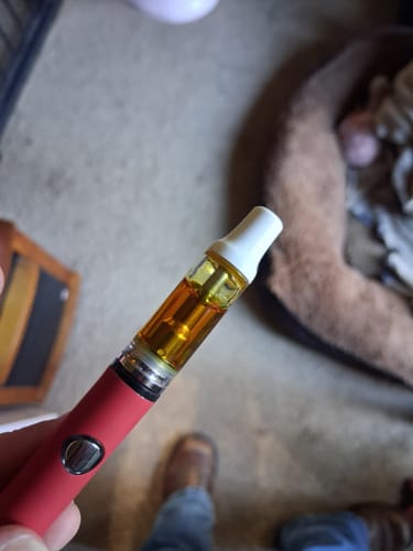 Customer's KIND 510 Thread THCa Live Resin cartridge with a white mouthpiece attached to a red battery.