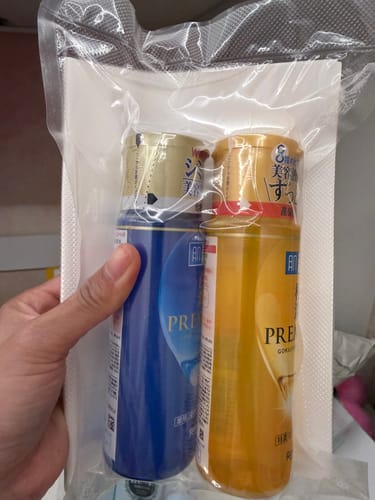 Customer's Hada Labo Premium Whitening Lotion bottles in sealed clear plastic packaging held by a hand.