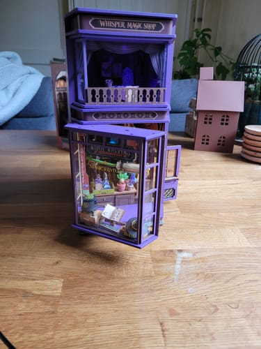 Customer's Robotime Book Nook Whisper Magic Shop, a purple wooden miniature display sitting on a wooden table.